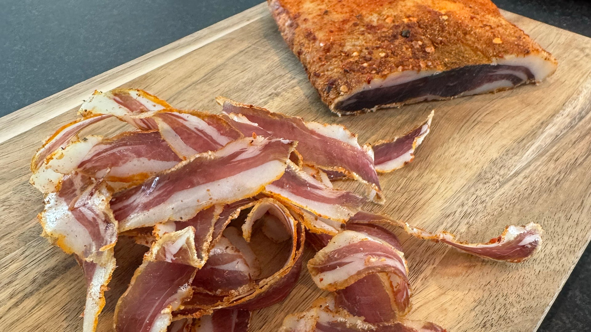 Sliced cured wild boar meat on a wooden cutting board